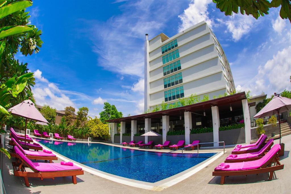 een hotel met paarse ligstoelen en een zwembad bij Amaranth Suvarnabhumi Hotel in Lat Krabang