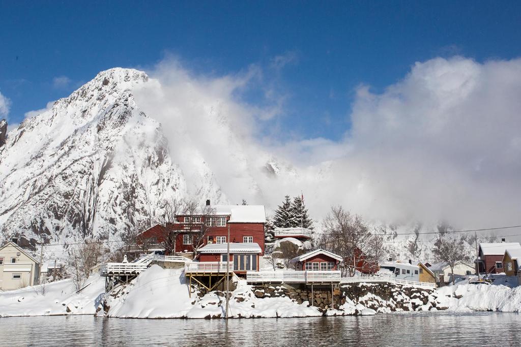 een huis in de sneeuw naast een berg bij Aabor Buene-Svolvær in Svolvær