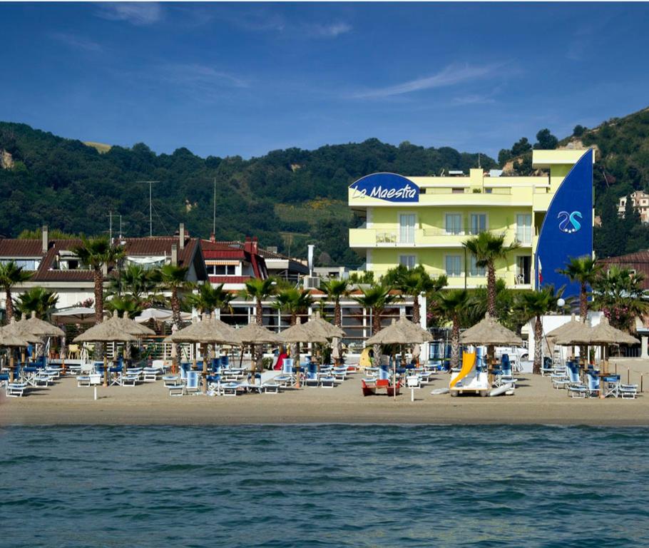 ein Strand mit Stühlen und Sonnenschirmen sowie ein Hotel in der Unterkunft Hotel La Maestra in Grottammare