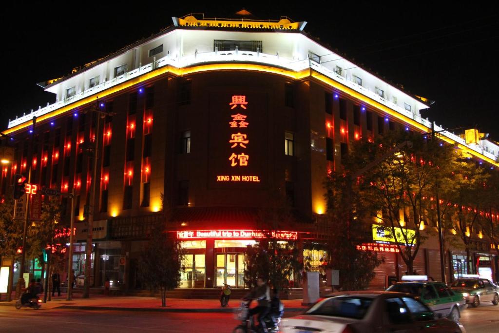 un bâtiment avec un panneau en haut de celui-ci la nuit dans l'établissement Xing Xin Hotel, à Dunhuang