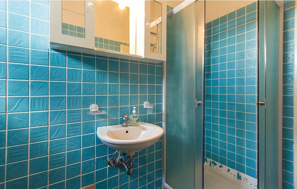 W wyłożonej niebieskimi kafelkami łazience znajduje się umywalka i lustro. w obiekcie Apartments Ivo 1328 w Fažanie