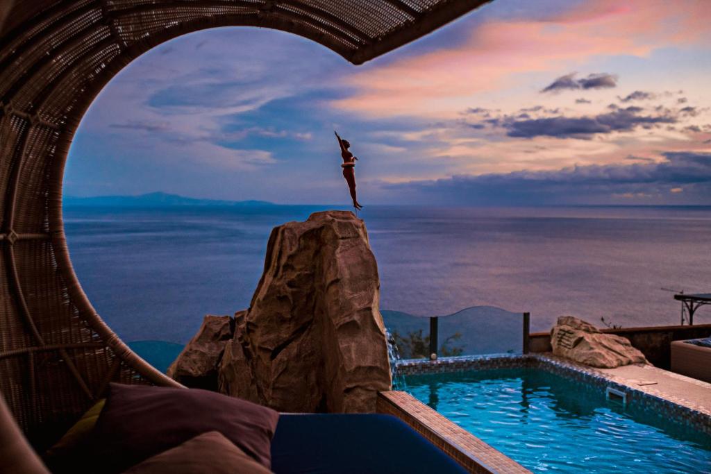 a person jumping off a rock into a swimming pool at Hotel Margherita in Praiano