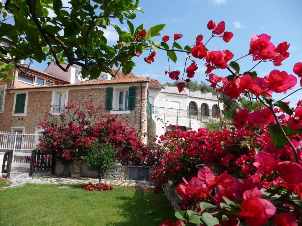 a house with red flowers in front of a yard at Cà dei Conti in San Bartolomeo al Mare