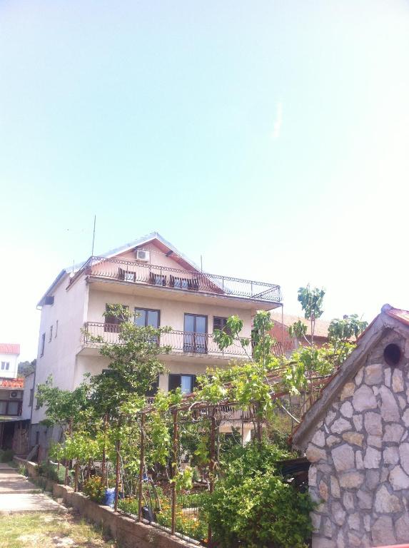 ein Gebäude auf einem Hügel mit Bäumen davor in der Unterkunft Apartment Floral in Brodarica