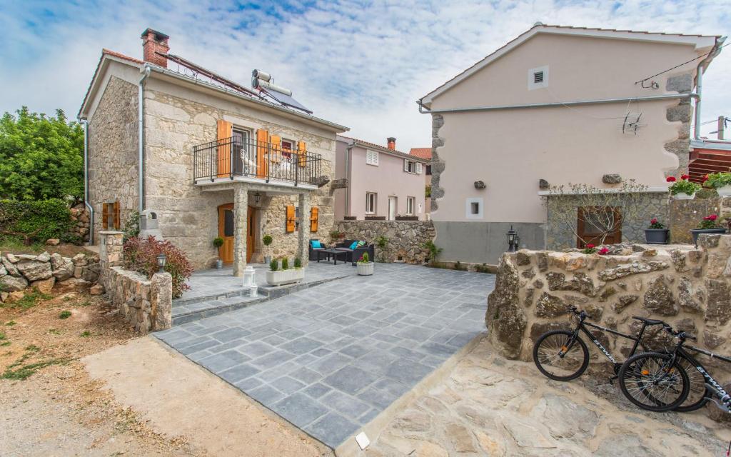 a stone house with a courtyard in front of a building at Holiday Home Eredità in Krk