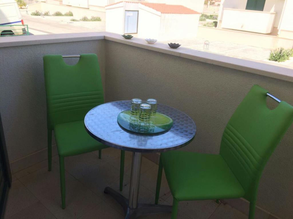 d'une table et de deux chaises vertes sur un balcon. dans l'établissement Studioapartman Loris, à Vodice