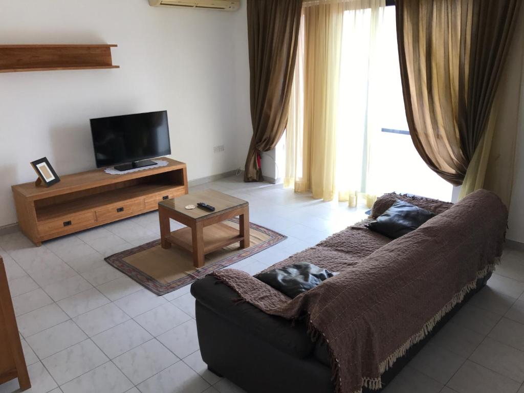 a living room with a couch and a tv at Swieqi Semi Detached Maisonette in St Julian's