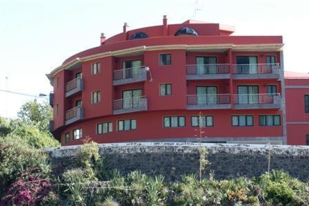 ein rotes Gebäude mit Balkon auf der Seite in der Unterkunft Aparthotel El Galeón in Santa Cruz de la Palma