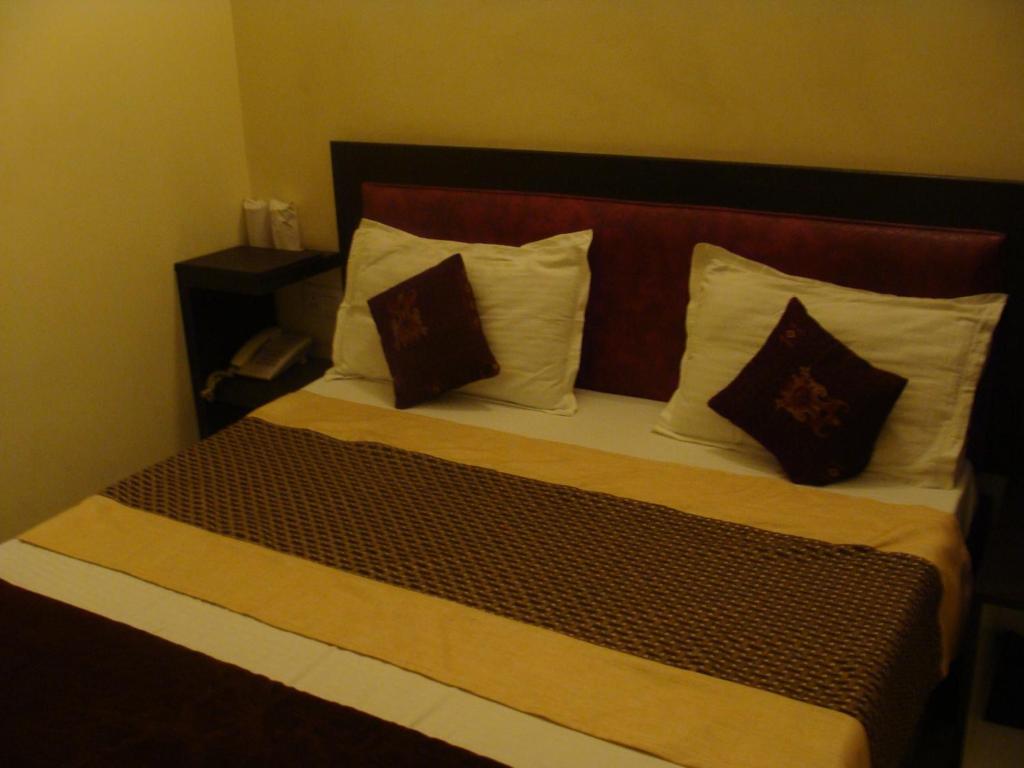 Bett in einem Hotelzimmer mit zwei Kissen in der Unterkunft Hotel Abhinandan Grand in Dehradun