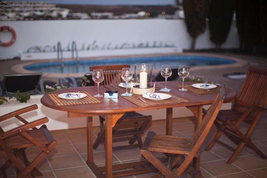 een houten tafel met wijnglazen en een kaars erop bij Villa Benita in Playa Blanca