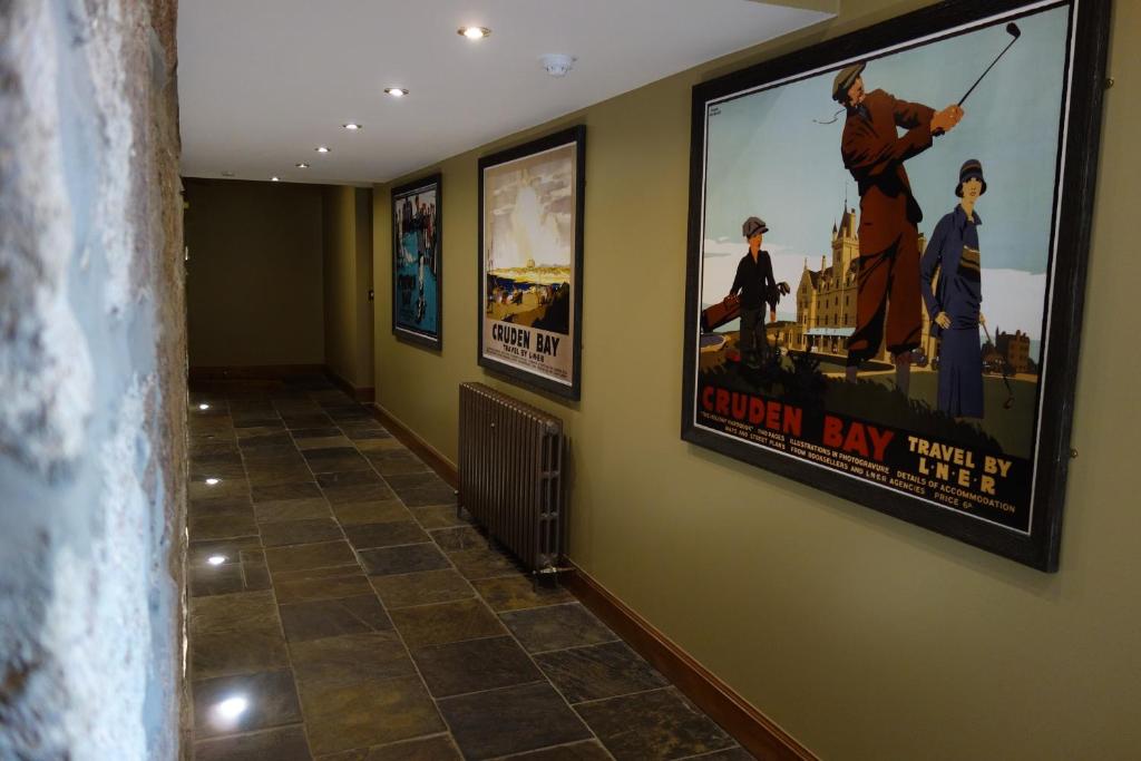 a hallway with posters on the walls of a building at Kilmarnock Arms Hotel in Cruden Bay