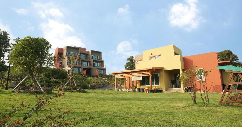 a group of buildings in a yard with a grass field at Oasis Pension in Seogwipo