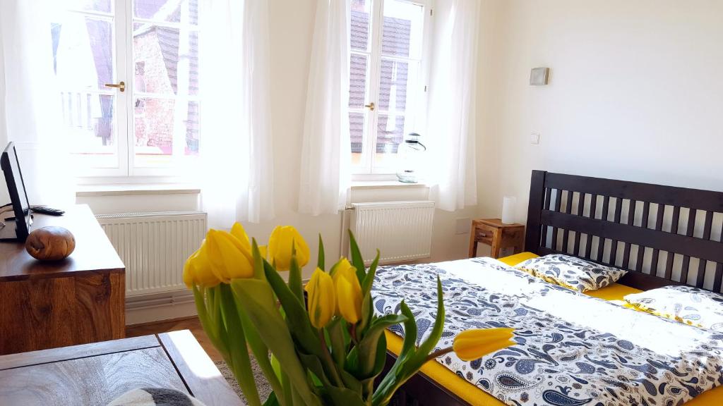 ブロウモフにあるApartmány u náměstíのベッドルーム1室(テーブルに黄色い花のベッド1台付)