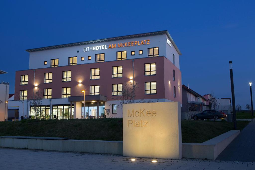 un grand bâtiment avec un panneau devant lui dans l'établissement CityHotel am McKeePlatz, à Crailsheim