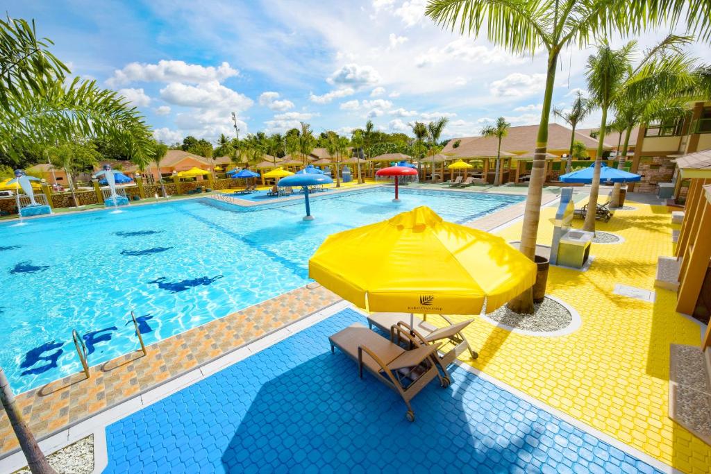 uma piscina com um guarda-sol amarelo e cadeiras ao lado em Kabaleyan Cove Resort em San Carlos