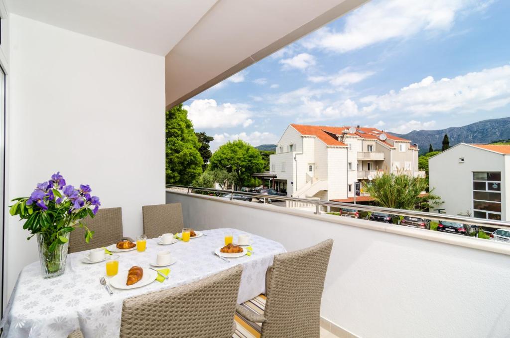 balcón blanco con mesa, sillas y ventana grande en Apartments Eva, en Dubrovnik
