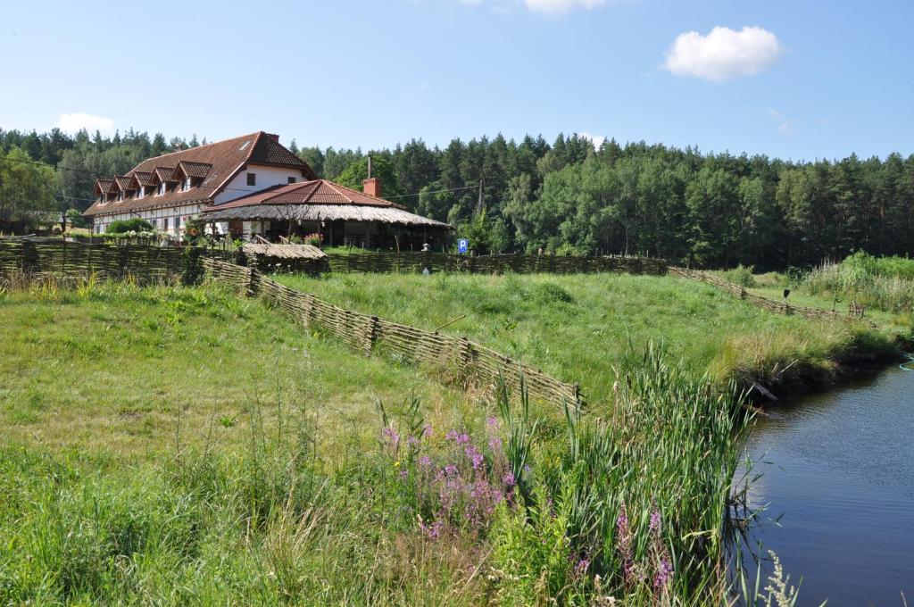 a house on a hill next to a river at Pensjonat Dolina Wierzby in Olsztyn