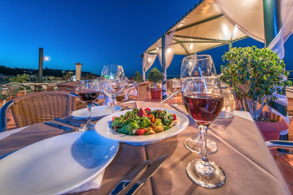 a table with wine glasses and a plate of food at Strada Marina Hotel in Zakynthos