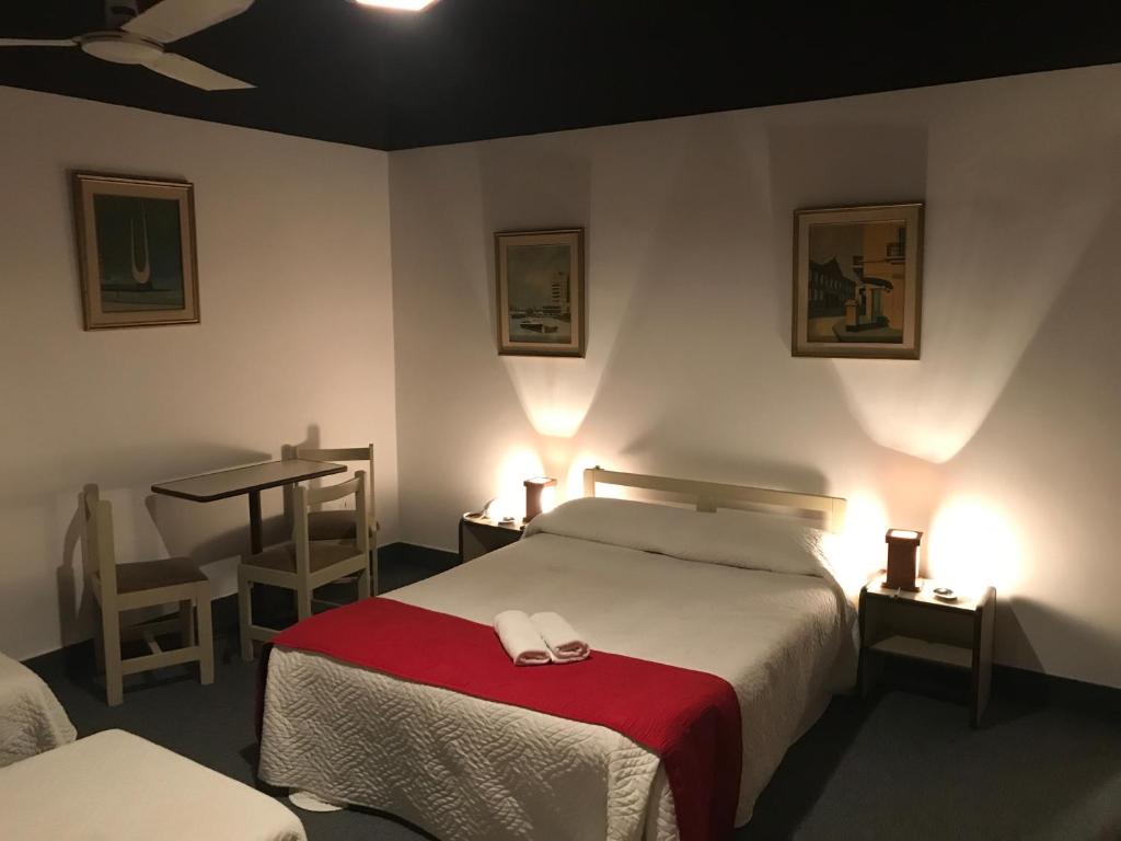 een hotelkamer met een bed met een rode deken bij Hotel Antares in Montevideo