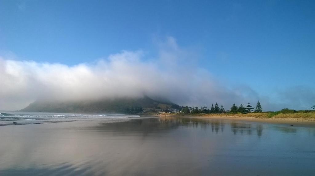 a foggy beach with a mountain in the background at @ the beach & not quite @ the beach Holiday Cottages - Stanley in Stanley