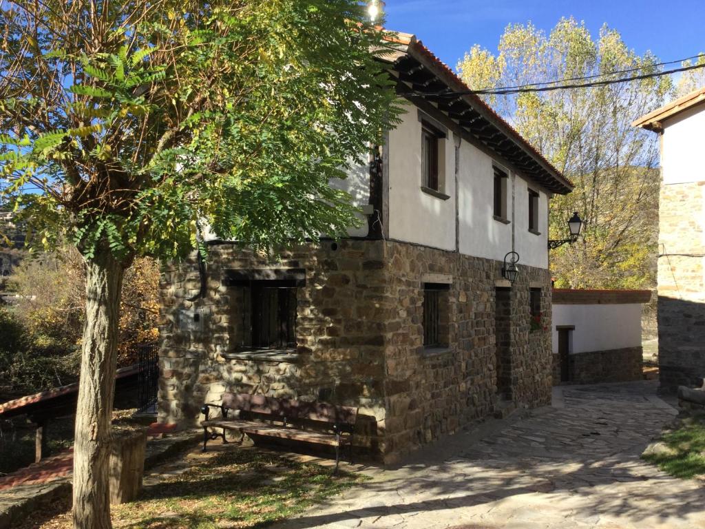 an old stone house with a tree in front of it at Casa Rural Tío Conejo in San Román de Cameros