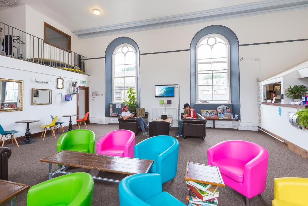 a room with chairs and tables and people sitting in them at Cohort Hostel in St Ives