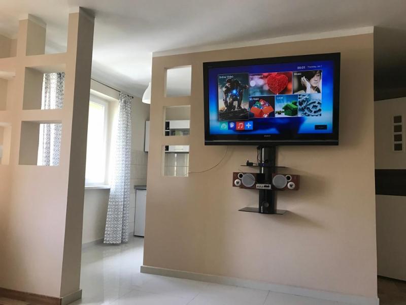 TV de pantalla plana en la pared de la sala de estar. en Apartament Deluxe Arcon, en Siemianowice Śląskie