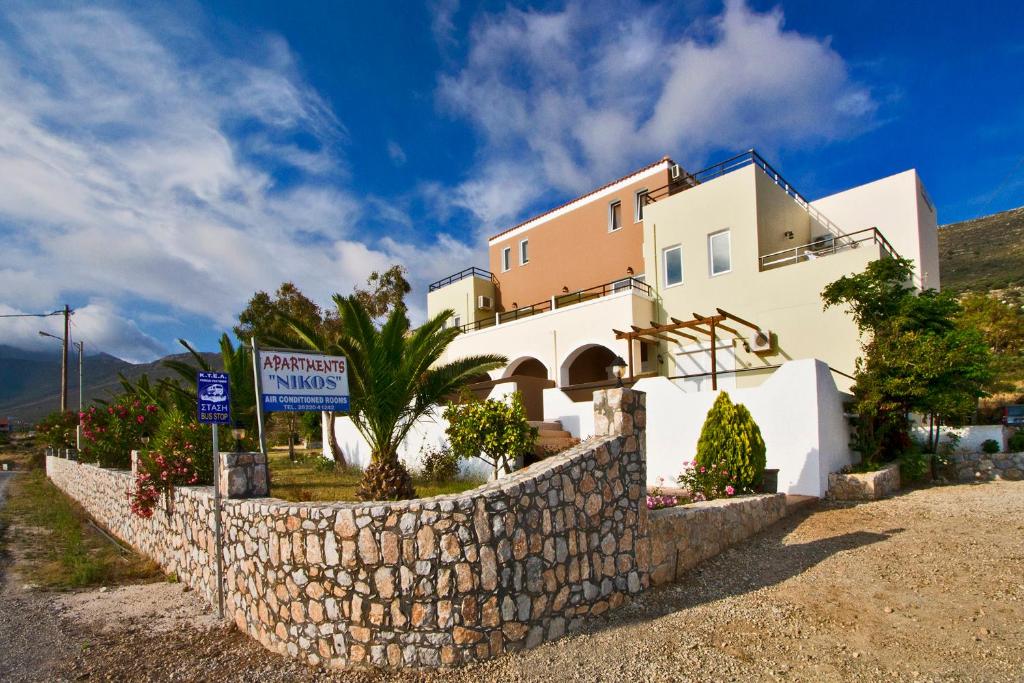 a house with a stone wall next to a building at Nikos Apartments in Falasarna