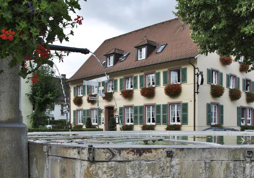 ein Gebäude mit grünen Fensterläden und einem Brunnen davor in der Unterkunft Landgasthof Rebstock Weil am Rhein / Basel in Weil am Rhein