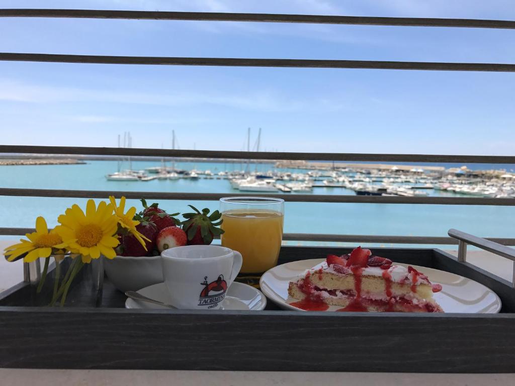 a tray with a piece of cake and a glass of orange juice at Hotel Aliai in Sciacca