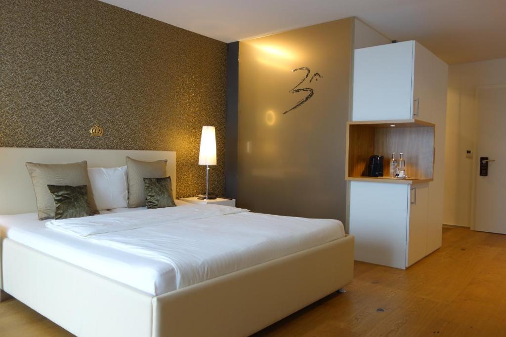 a bedroom with a large white bed and a kitchen at Hotel AVA in Sempach Station