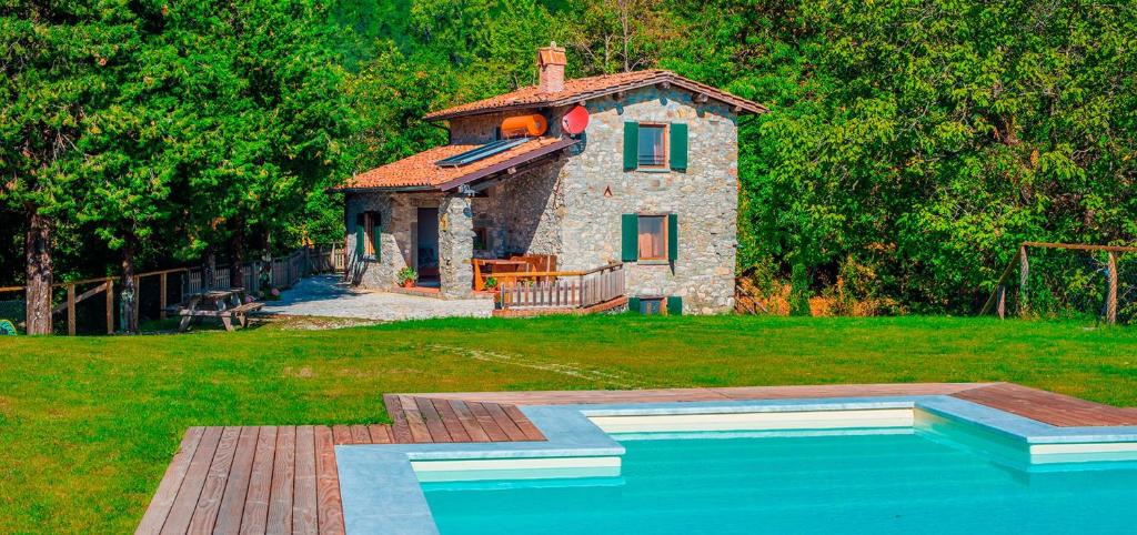 una pequeña casa de piedra con una piscina frente a ella en Casa Pescaglia, en Pescaglia