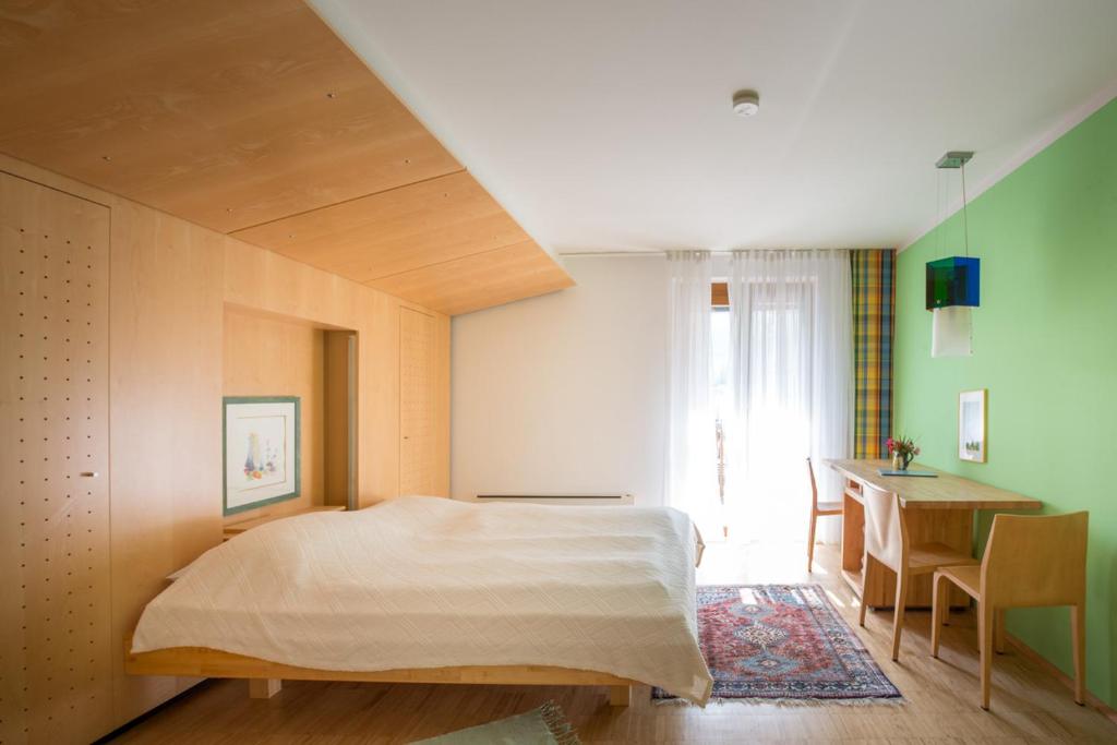 a bedroom with a large bed and a desk at Frühstückspension "Schlosswirt" in Ossiach