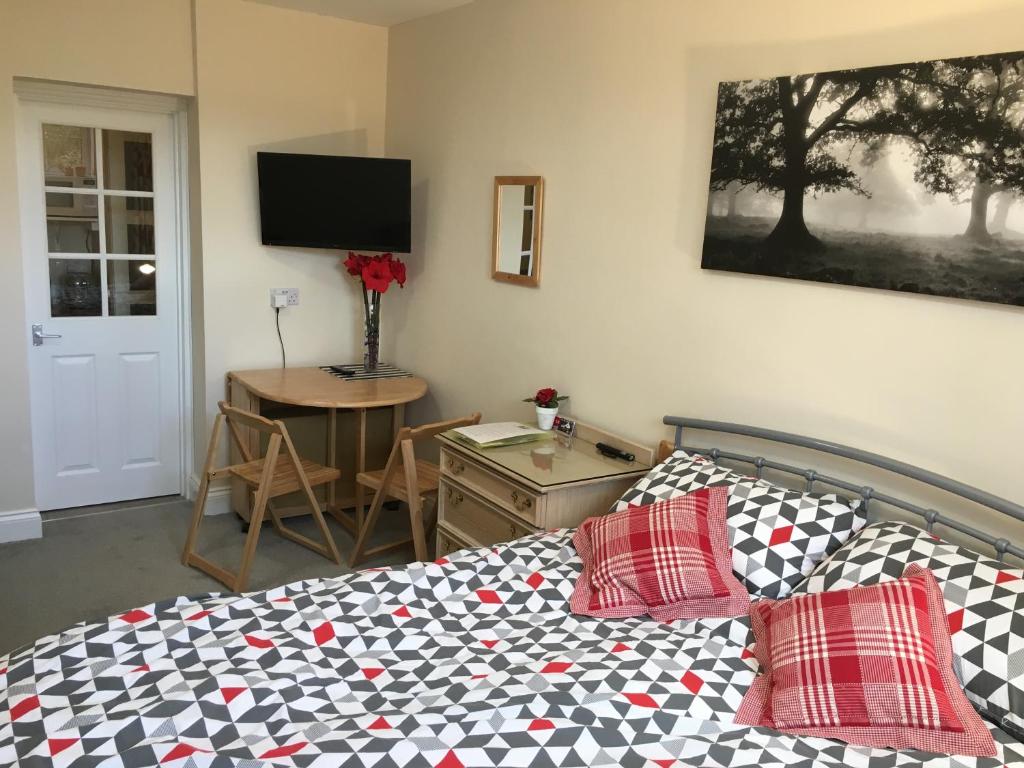 a bedroom with a bed and a desk with a television at High Banks studio in Sevenoaks