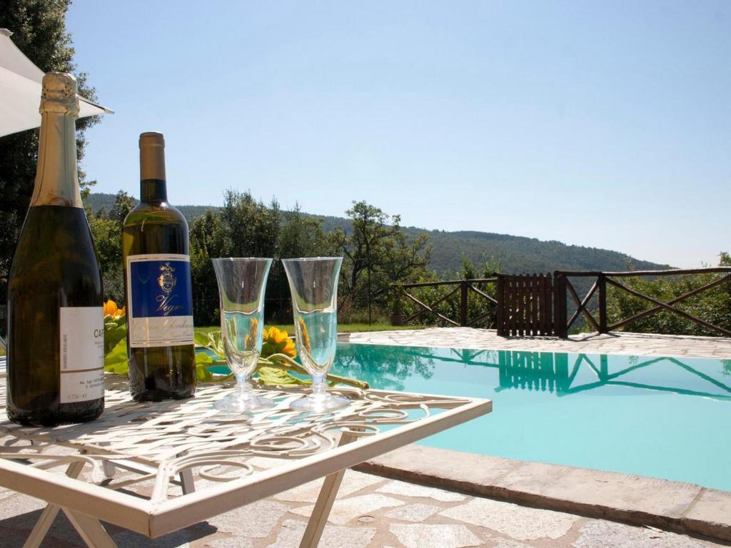 コルトーナにあるVilla Leccioのスイミングプールのそばのテーブル(ワインボトル、グラス付)