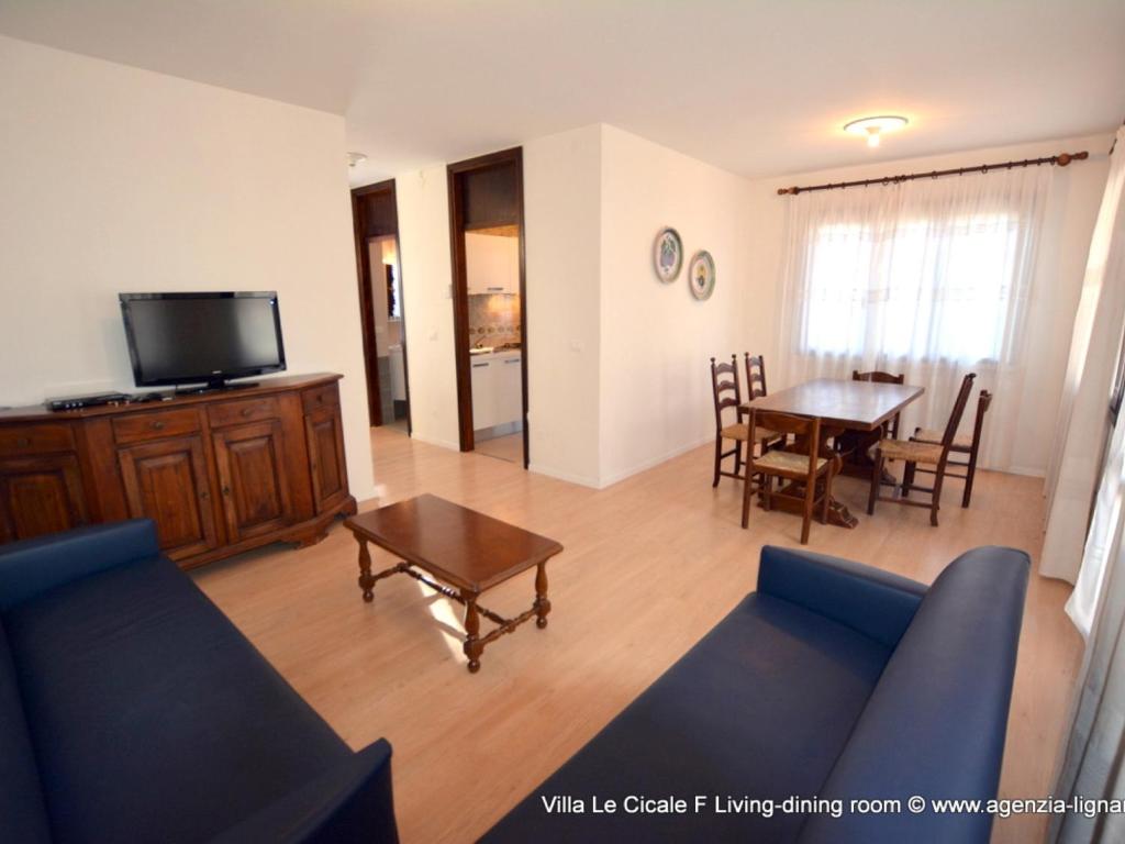 a living room with a blue couch and a table at Lignano Pineta Big Villa in Lignano Sabbiadoro