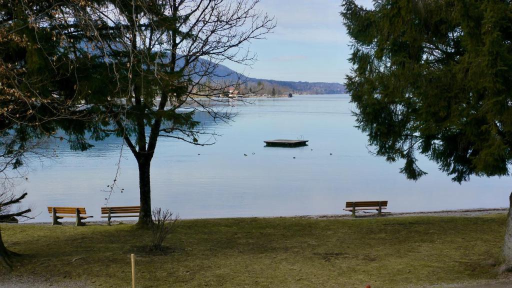 dois bancos sentados ao lado de um lago com um barco em Apartment Kobellstrasse em Rottach-Egern
