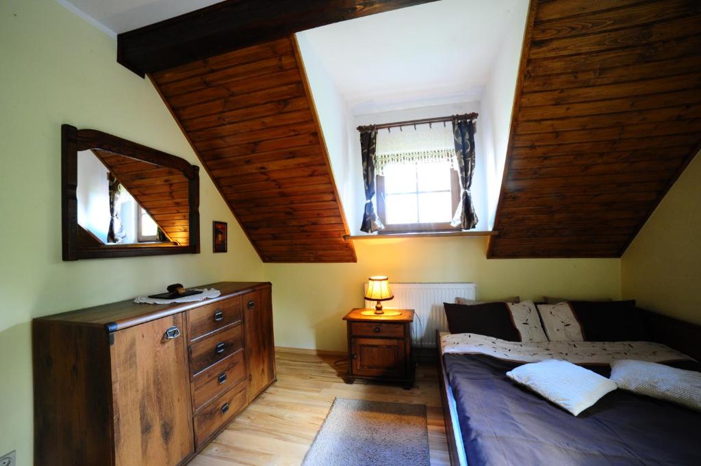 a bedroom with a bed and a dresser and two windows at Przystań Jaskółka in Ruciane-Nida