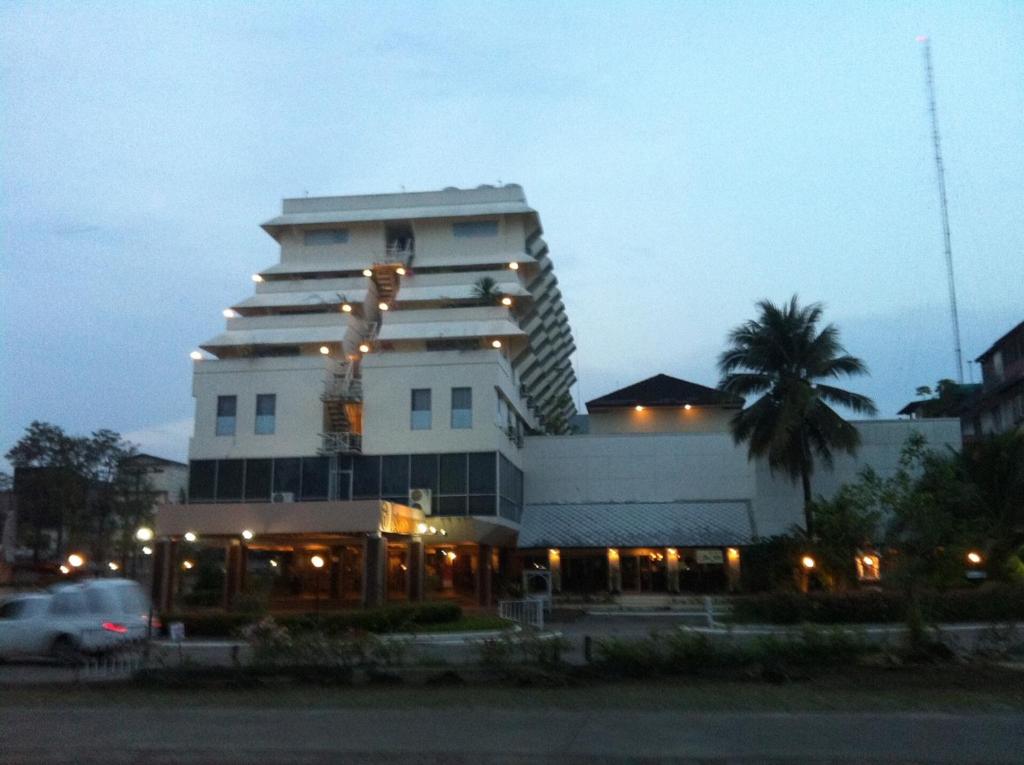 a large white building with a palm tree in front of it at Paradorn Inn in Chumphon