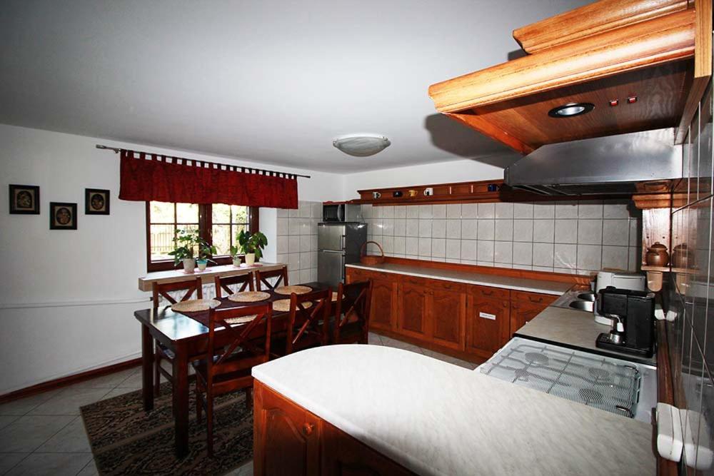 una cocina con armarios de madera, mesa y sillas en Poronin Apartament, en Poronin