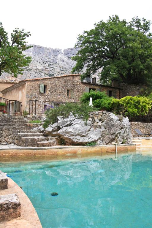 a pool of blue water in front of a building at Le Moulin en Provence in Saint-Antonin-sur-Bayons