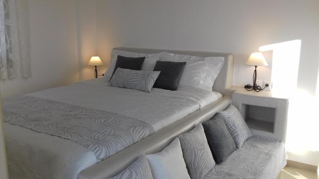 a large white bed in a room with two lamps at Notos Studios in Schinoussa