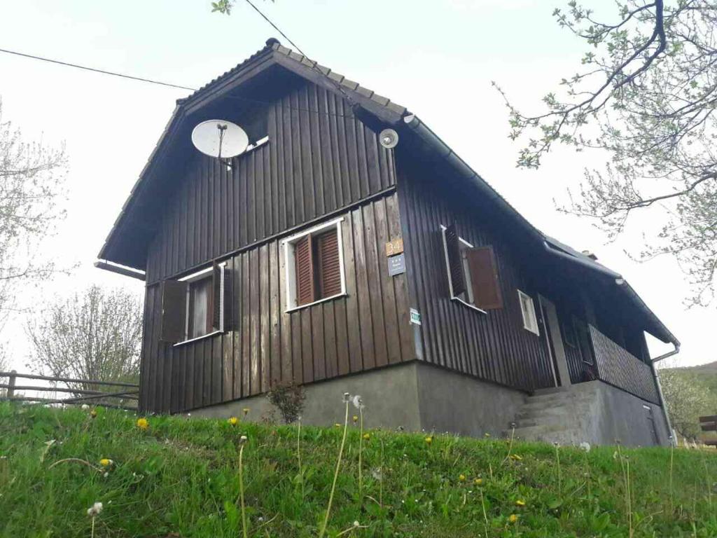 a house with a gambrel roof on top of a hill at Apartment Marija in Poljanak