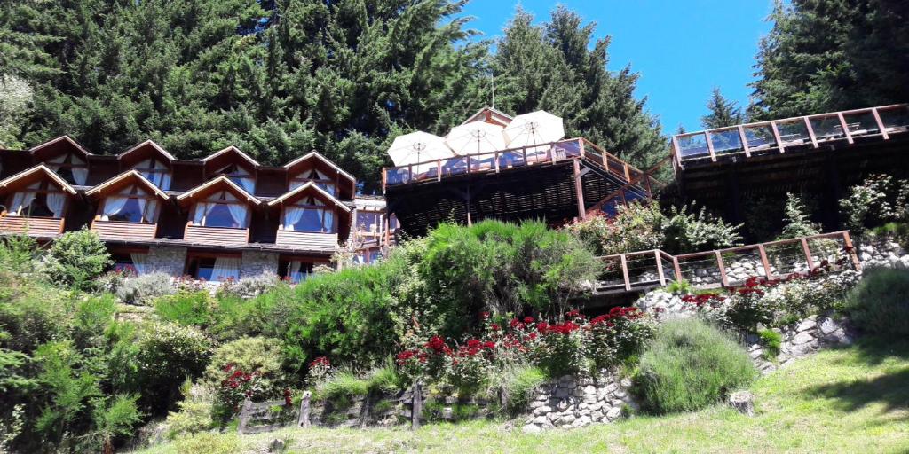 a group of buildings on a hill with flowers at Dos Bahias Lake Resort in Villa La Angostura
