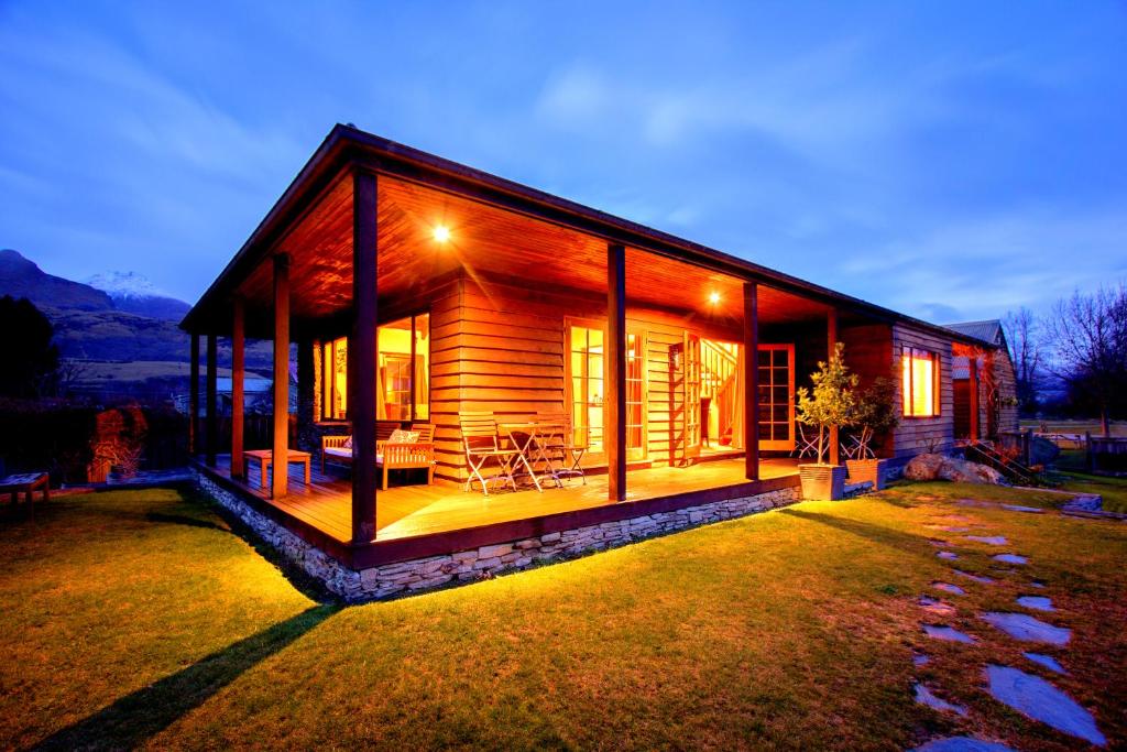 una cabaña de madera con las luces encendidas por la noche en Glenorchy Lake House, en Glenorchy