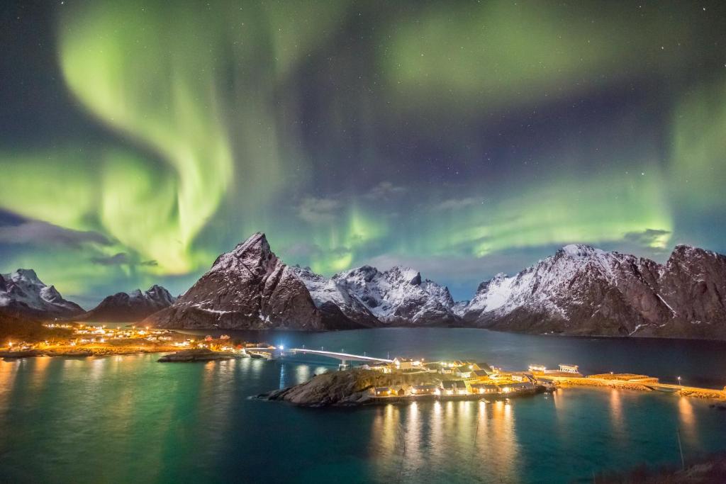 ein Bild einer Stadt mit der Aurora im Himmel in der Unterkunft Sakrisøy Gjestegård - Manor House in Sakrisøy - Solbakken anno 1880 in Reine