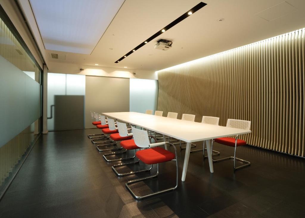 a conference room with a white table and red chairs at HOTEL MYSTAYS Ochanomizu Conference Center in Tokyo