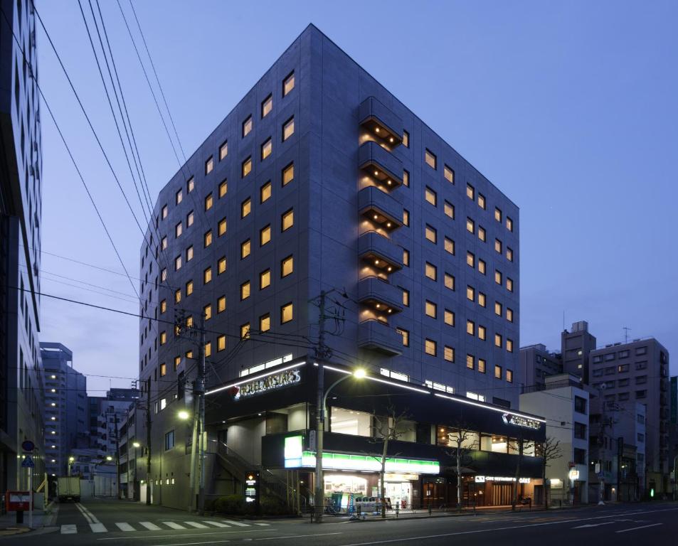 um edifício alto numa rua da cidade à noite em HOTEL MYSTAYS Ochanomizu Conference Center em Tóquio