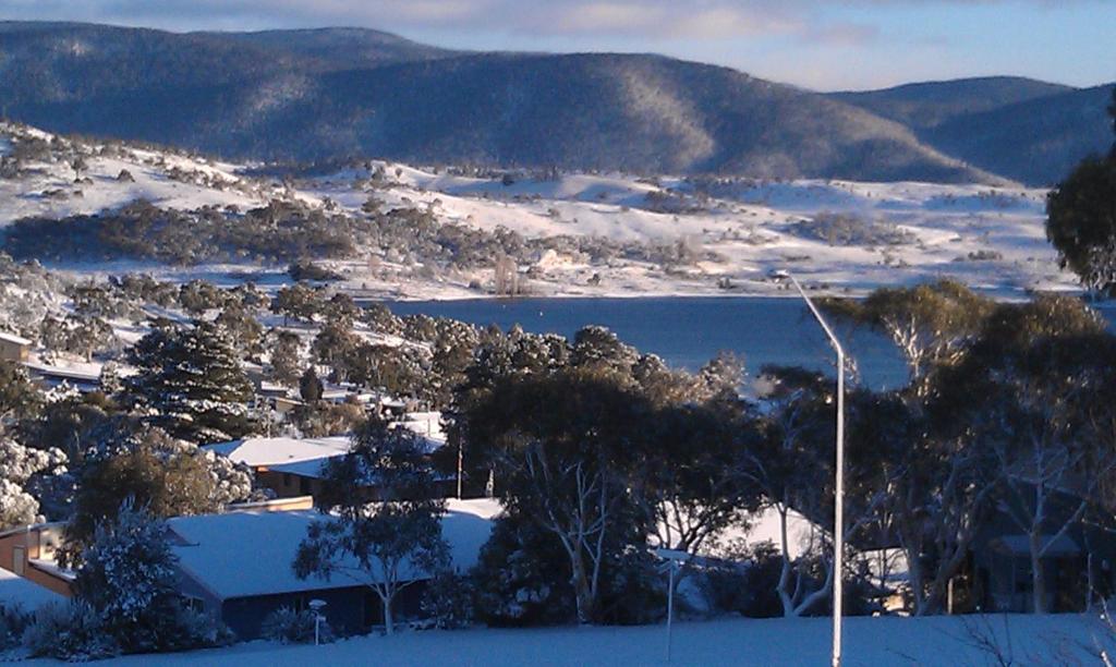 a snow covered town with a street light and a lake at Jindabyne Guest House in Jindabyne