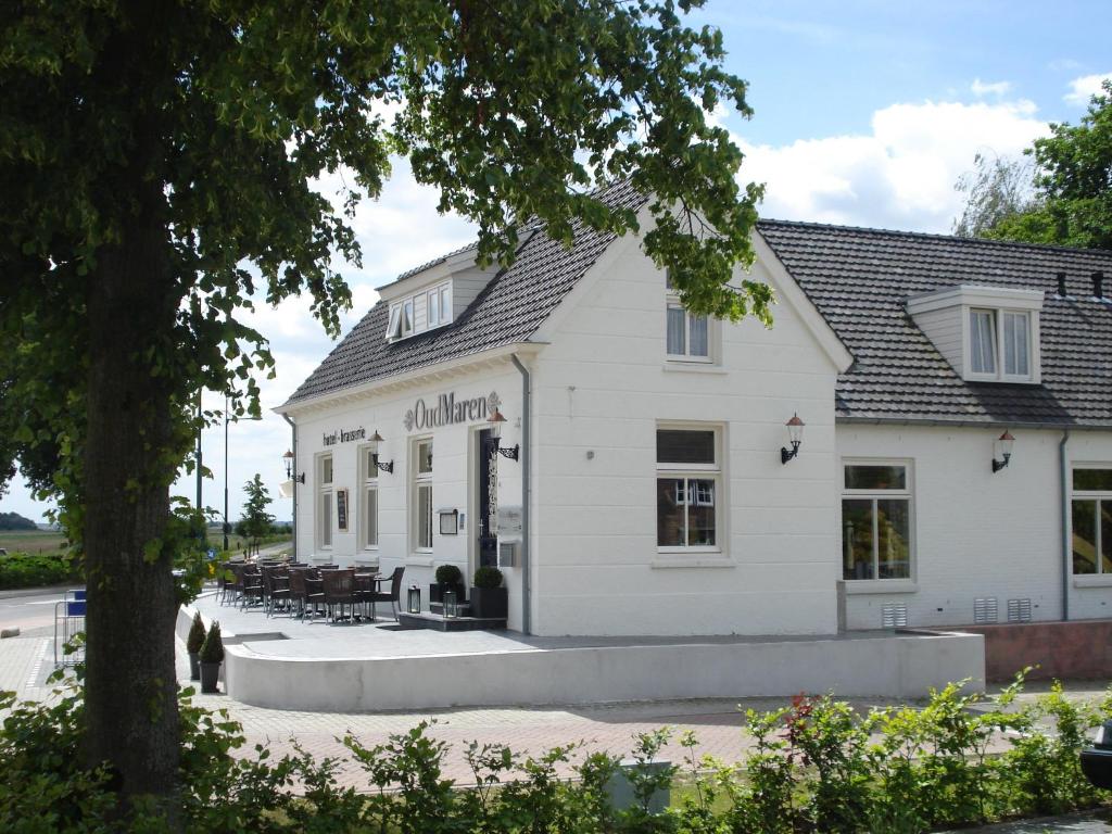 een wit gebouw met tafels en stoelen buiten bij Hotel Brasserie Oud Maren in Maren-Kessel